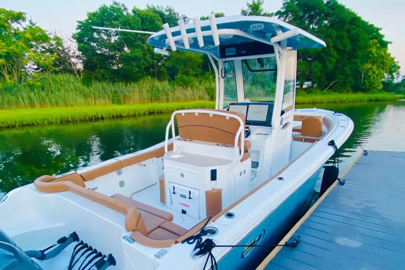 Slide: The Image of 2021 Sea Hunt Ultra 265 SE boat docked by lush greenery. - 5