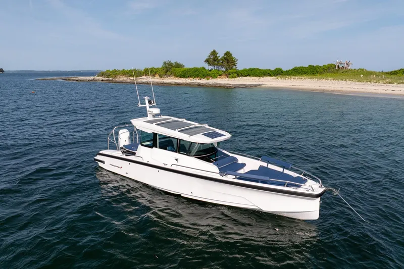 Slide: The Image of 2026 Axopar 29 XC Cross Cabin boat cruising near a scenic shoreline. - 10