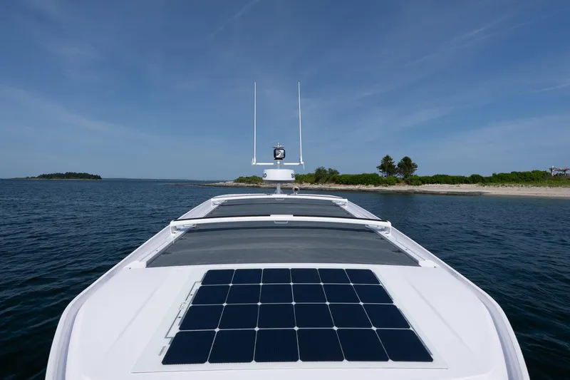 Slide: The Image of 2026 Axopar 29 XC Cross Cabin with solar panels on the roof, near a scenic shoreline. - 24