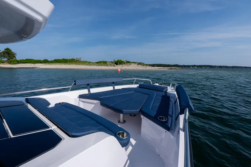 Slide: The Image of 2026 Axopar 29 XC Cross Cabin boat with blue seating, near a scenic shoreline. - 25