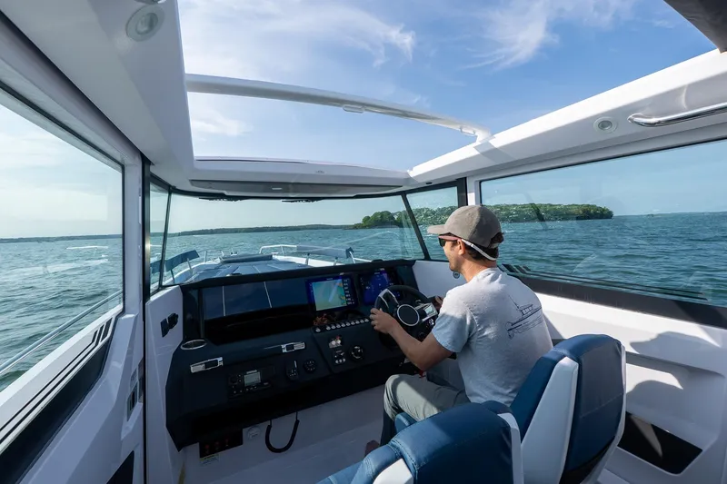 Slide: The Image of 2026 Axopar 29 XC Cross Cabin navigating open waters, interior view with driver. - 6
