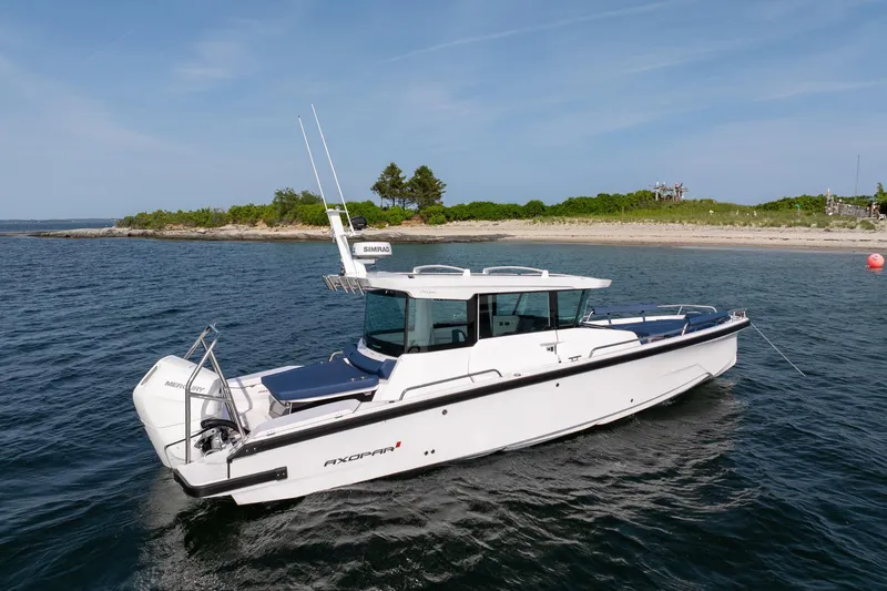Slide: The Image of 2026 Axopar 29 XC Cross Cabin boat on calm water near a scenic shoreline. - 8