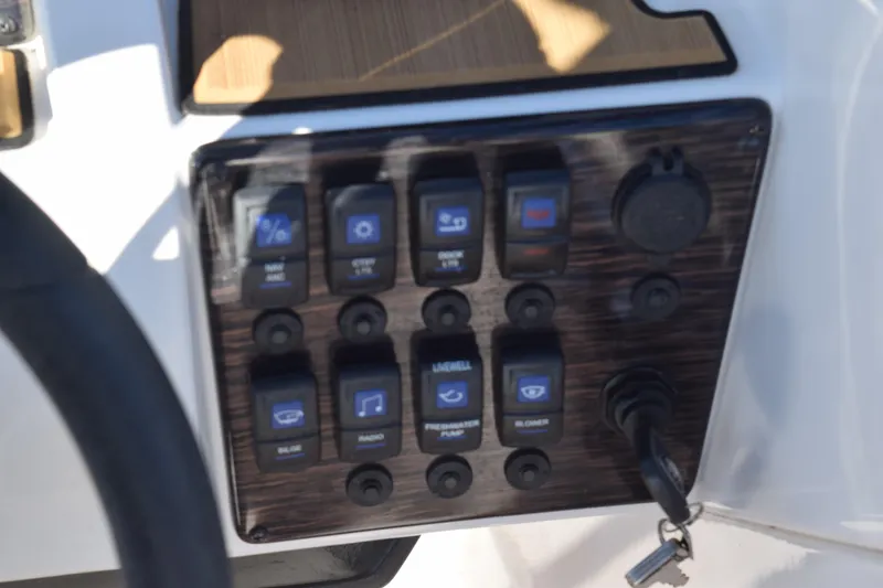 Slide: The Image of Control panel of 2023 Starcraft SVX 210 IO boat with various switches and key ignition. - 17