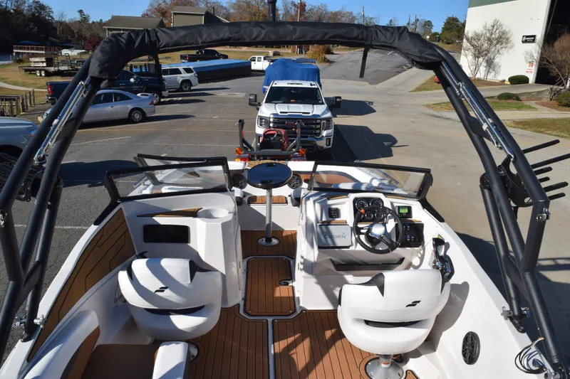 Slide: The Image of 2023 Starcraft SVX 210 IO boat interior with steering wheel and seating, parked on a trailer. - 38