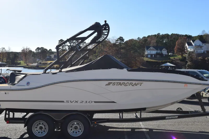 Slide: The Image of 2023 Starcraft SVX 210 IO boat on trailer, parked near a scenic waterfront. - 39