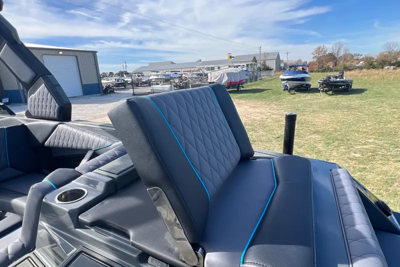 Slide: The Image of 2026 Tigé Z3 boat interior with quilted seats and cup holder, parked outdoors. - 8