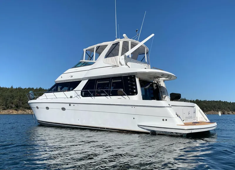 The Image of 2000 Carver 530 Voyager Pilothouse yacht on calm water, clear sky background. - 0