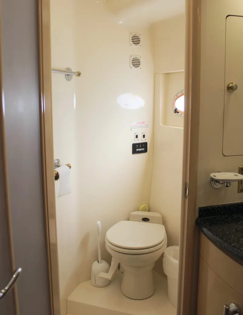 Slide: The Image of 2000 Carver 530 Voyager Pilothouse bathroom with toilet, sink, and porthole window. - 10
