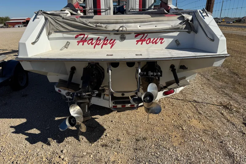 Slide: The Image of 1987 Chaparral Villain IV boat named "Happy Hour" with dual propellers, parked on gravel. - 7