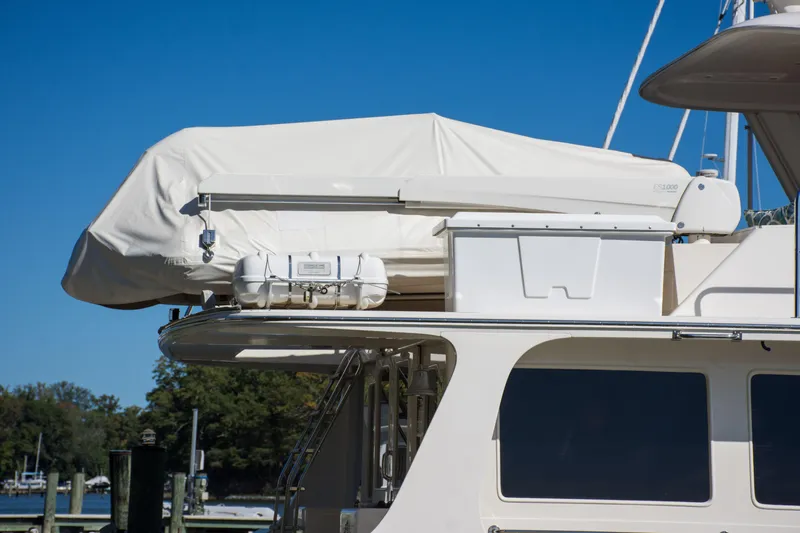 Slide: The Image of 2015 Fleming 55 yacht with covered equipment on deck, docked under clear blue sky. - 37