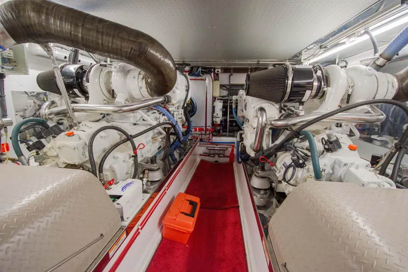 Slide: The Image of Engine room of a 2015 Fleming 55 yacht, featuring dual engines and red carpet flooring. - 50