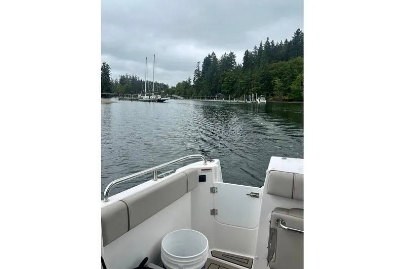 Slide: The Image of 2025 Cutwater C-248 Coupe boat view, marina with sailboats and trees in background. - 14