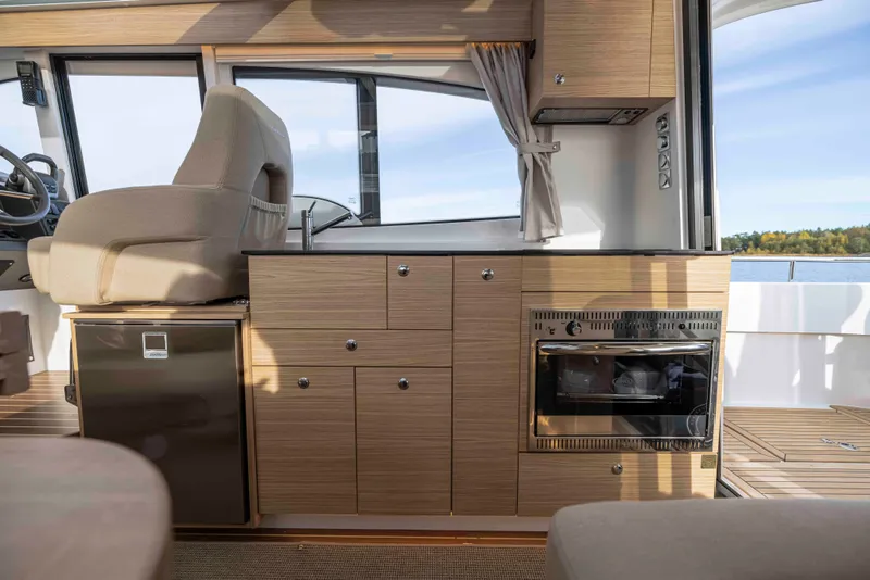Slide: The Image of Interior of 2025 Nimbus 365 Coupe, featuring modern kitchen and helm seat. - 16