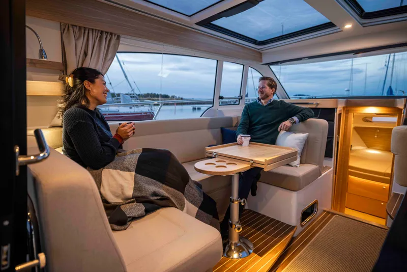Slide: The Image of Couple enjoying cozy interior of 2025 Nimbus 365 Coupe yacht with scenic marina view. - 20