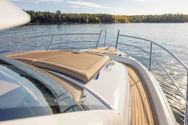 Slide: The Image of Luxurious 2025 Nimbus 365 Coupe yacht deck with sunbed, overlooking serene waters and forested shoreline. - 6