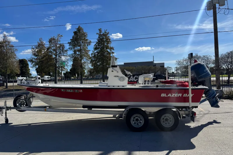 Slide: The Image of 2014 Blazer Bay 2170 boat on trailer, parked outdoors under clear blue sky. - 5