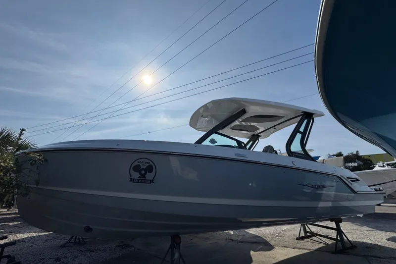 The Image of 2026 Monterey Elite 25 OB boat under sunny sky, displayed on stands. - 1
