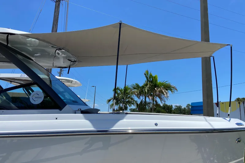 Slide: The Image of 2026 Monterey Elite 25 OB boat with sunshade, parked under clear blue sky. - 29