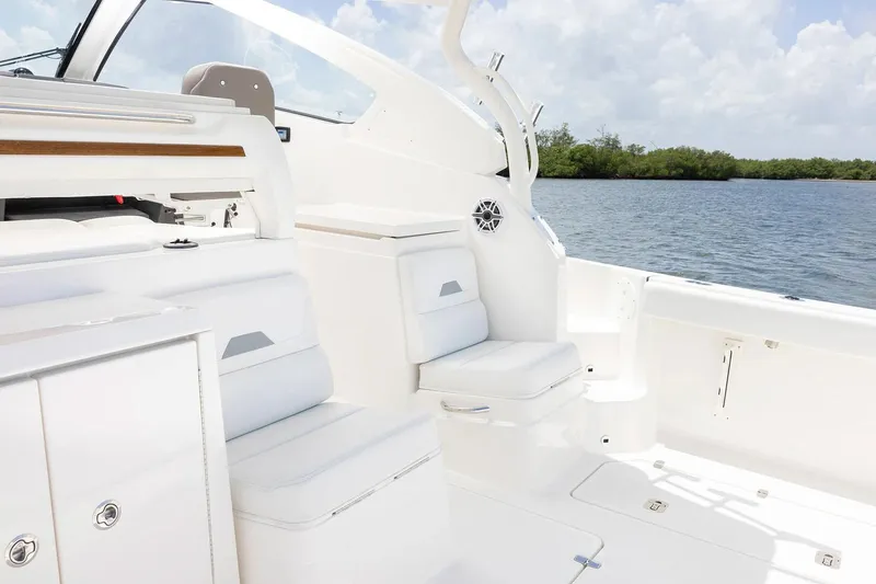 Slide: The Image of Manufacturer Provided Image: 2025 Pursuit OS 405 Offshore boat interior with white seating, near calm waters. - 13