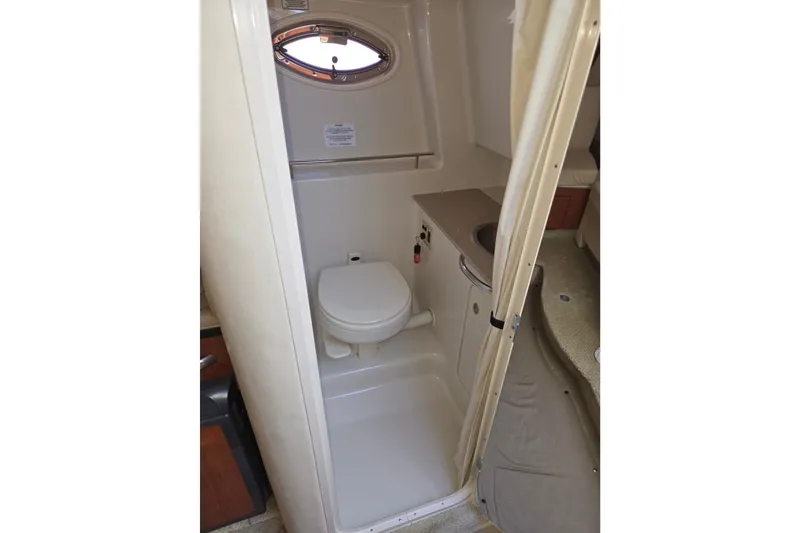 Slide: The Image of 2007 Sea Ray 290 Sundancer bathroom with toilet, sink, and porthole window. - 18