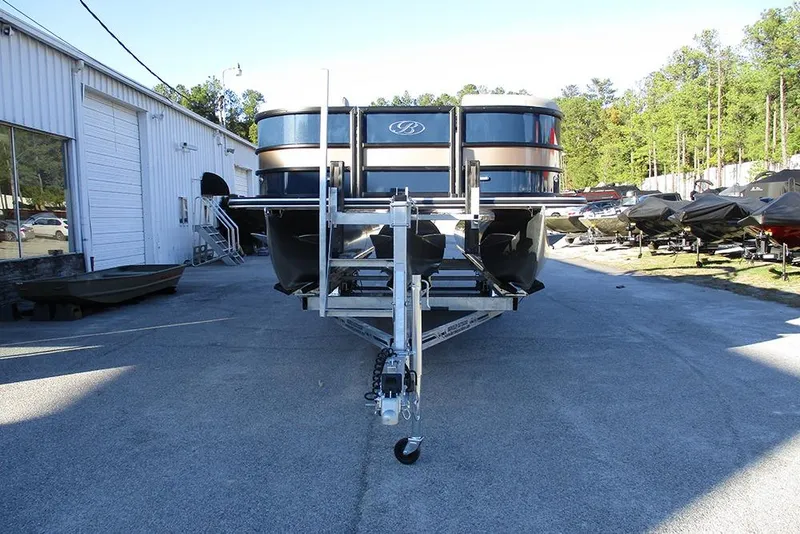 Slide: The Image of 2026 Bentley Pontoons Legacy 243 Swingback on trailer, parked outdoors near a warehouse. - 3