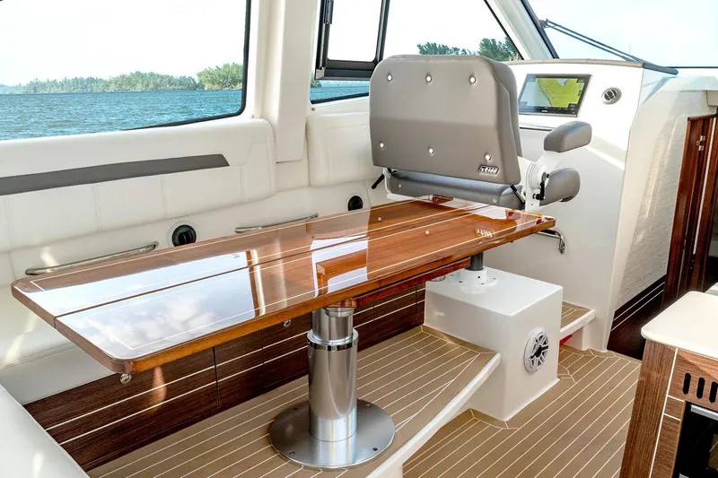 Slide: The Image of Manufacturer Provided Image: Luxurious interior of 2025 Pursuit OS 445 Offshore boat with polished wood table and seating. - 11