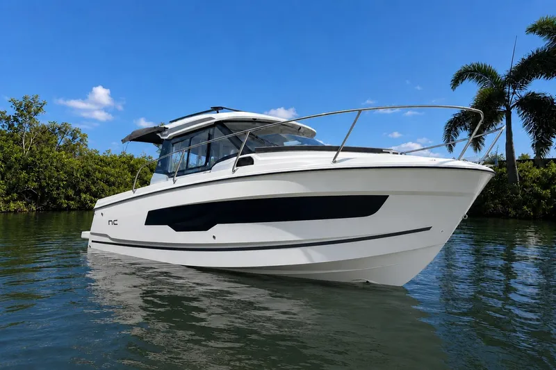 The Image of 2026 Jeanneau NC 795 Series 2 boat on calm water, surrounded by lush greenery. - 0