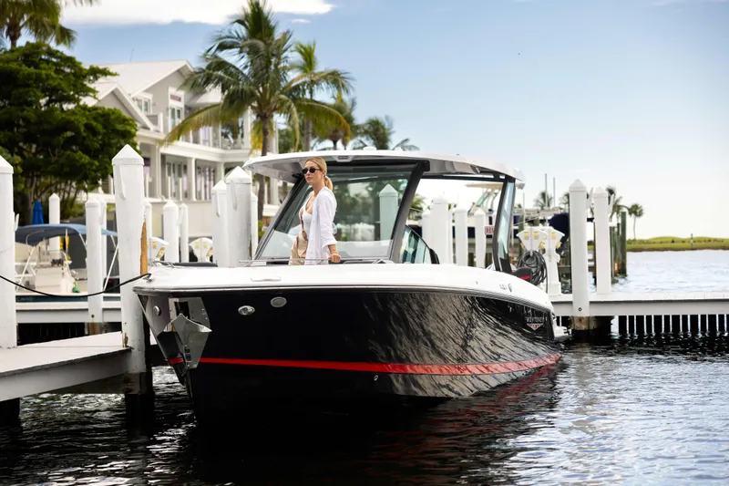 Slide: The Image of 2026 Monterey Elite 30 OB boat docked at marina with palm trees and waterfront homes. - 16