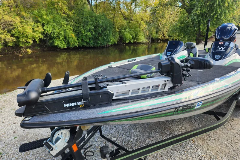 Slide: The Image of 2019 Skeeter FX21 bass boat with Minn Kota trolling motor by a riverbank. - 12