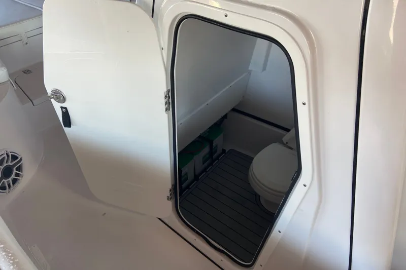 Slide: The Image of 2026 Sportsman Masters 267 Bay Boat interior with open door revealing compact bathroom. - 23
