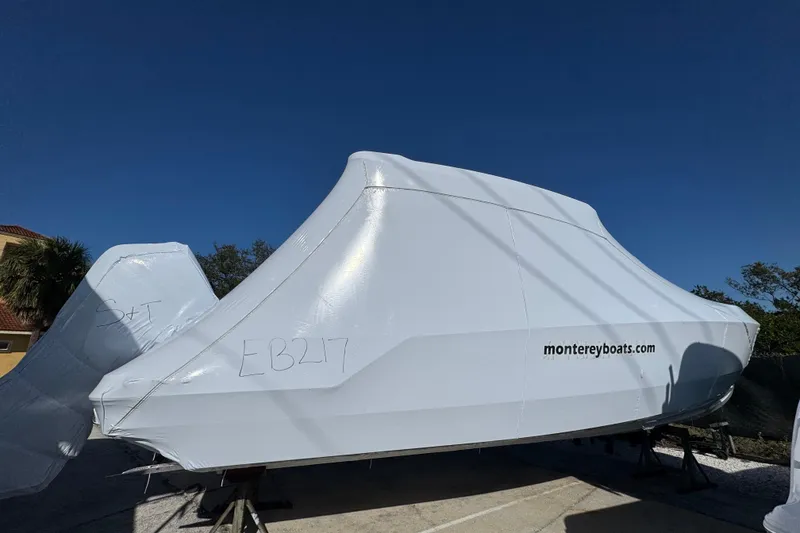 Slide: The Image of 2026 Monterey Elite 27 OB boat covered, displayed outdoors under clear blue sky. - 8