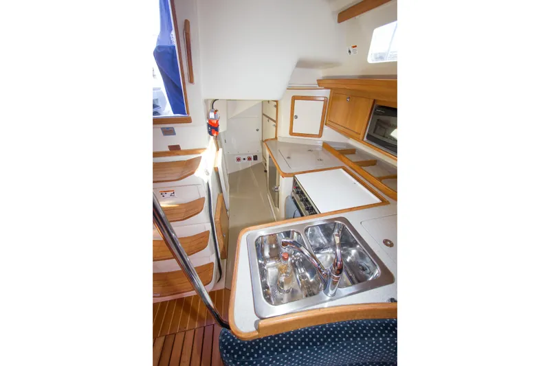 Slide: The Image of Interior of 2008 Catalina 42 MkII yacht, featuring a compact kitchen with wooden cabinetry. - 17