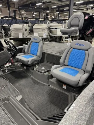Slide: The Image of 2026 Ikon Boats LXL20 interior with blue and gray seating, showcased in a boat showroom. - 3