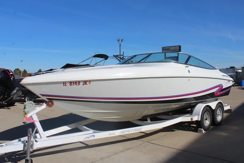 Slide: The Image of 1996 Baja 232 speedboat on trailer, white with red accents, parked outdoors. - 4