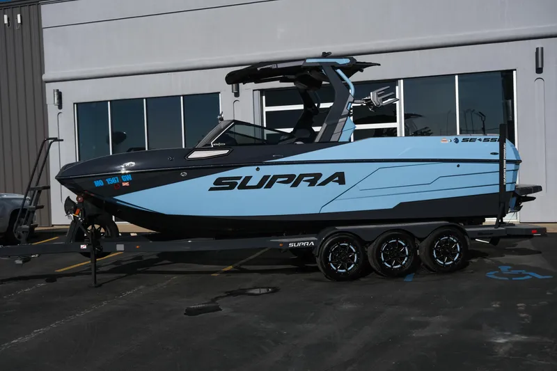 Slide: The Image of 2025 Supra SE550 boat on trailer, parked outside a building. - 1