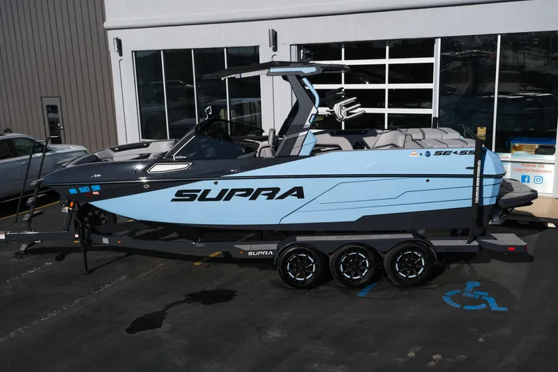 Slide: The Image of 2025 Supra SE550 boat in light blue on a trailer outside a building. - 2