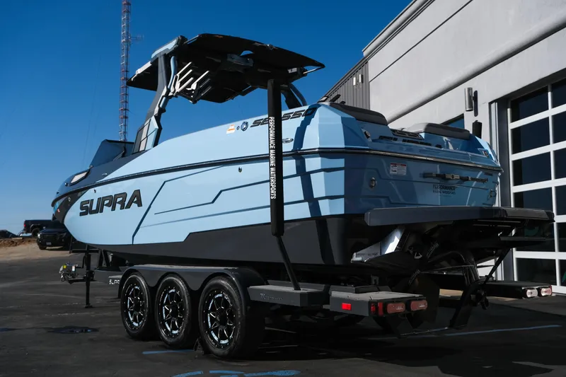 Slide: The Image of 2025 Supra SE550 boat on trailer, parked outside a building under clear blue sky. - 4