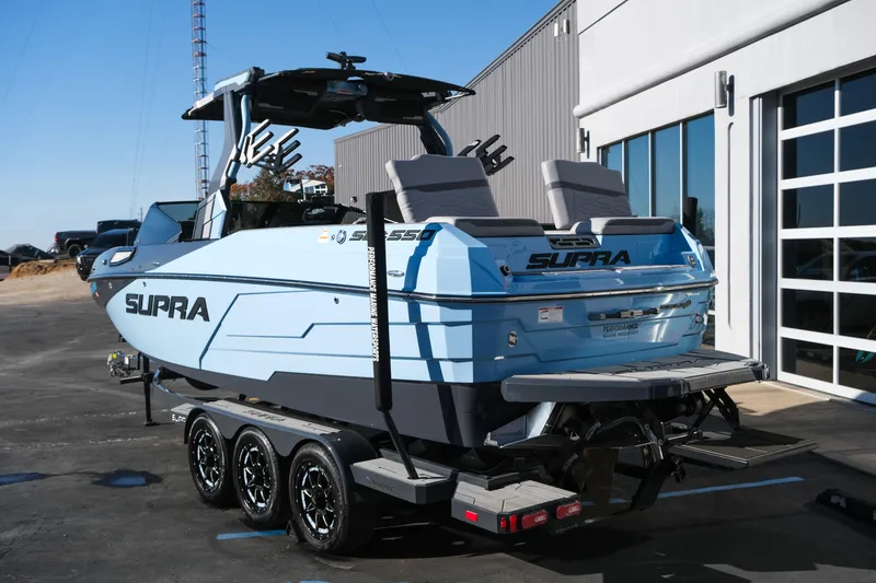Slide: The Image of 2025 Supra SE550 boat on trailer, parked outside a modern building. - 5