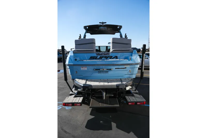 Slide: The Image of 2025 Supra SE550 boat rear view, blue exterior, parked on asphalt. - 7