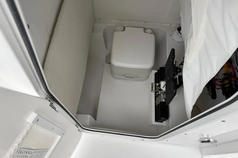 Slide: The Image of Interior of 2026 Sea Hunt Ultra 235 SE boat, featuring compact marine toilet. - 21