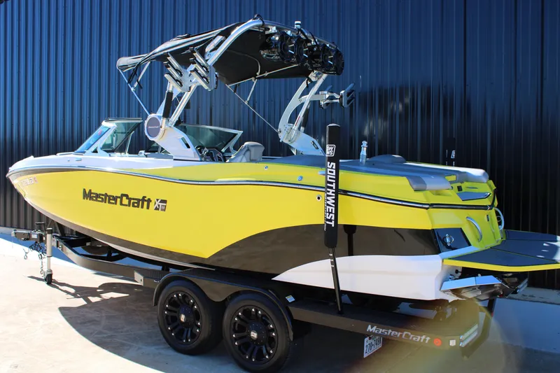 Slide: The Image of 2018 MasterCraft XT22 boat in vibrant yellow on a trailer, parked outdoors. - 3