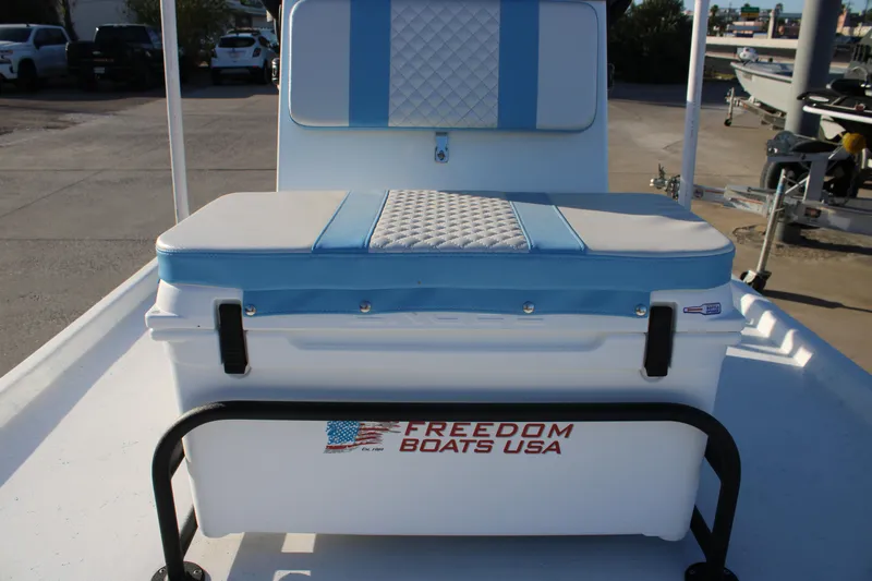 Slide: The Image of 2026 Freedom Boats Chiquita with cushioned seating and storage, parked outdoors. - 10