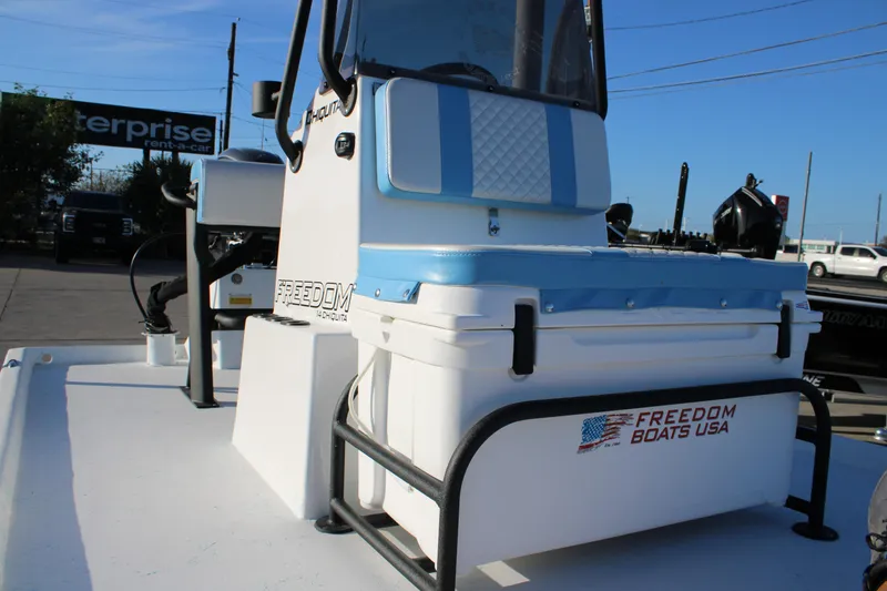 Slide: The Image of 2026 Freedom Boats Chiquita with blue and white seating, parked outdoors. - 11