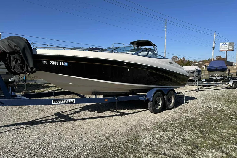 The Image of 1994 Crownline 225 BR boat on a trailer, parked outdoors under clear blue sky. - 0