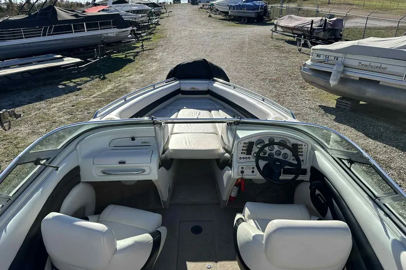 Slide: The Image of 1994 Crownline 225 BR boat interior with white seating and dashboard, parked among other boats. - 6