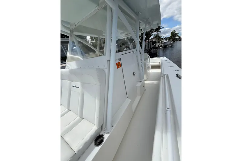 Slide: The Image of 2010 SeaHunter 40 boat interior with white seating and clear canopy, docked by a calm waterway. - 22
