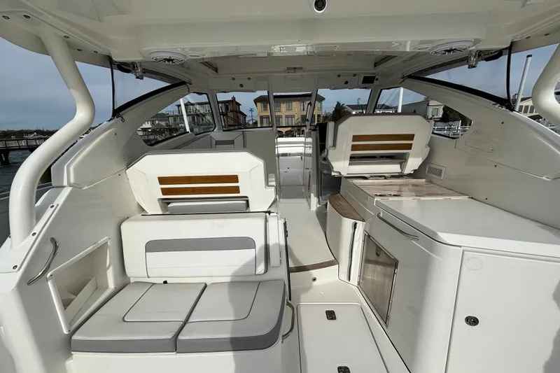 Slide: The Image of 2022 Pursuit DC 365 Dual Console interior with seating and storage, docked near waterfront homes. - 11