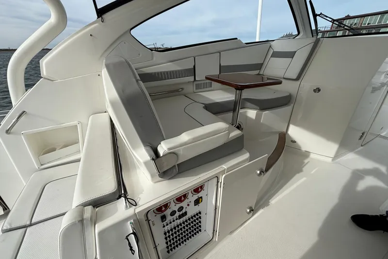 Slide: The Image of 2022 Pursuit DC 365 Dual Console interior with seating and wooden table by the water. - 18