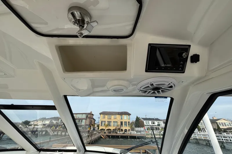 Slide: The Image of 2022 Pursuit DC 365 Dual Console boat interior with JL Audio system and waterfront view. - 29