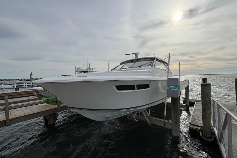 Slide: The Image of 2022 Pursuit DC 365 Dual Console boat docked on a lift at a marina. - 3